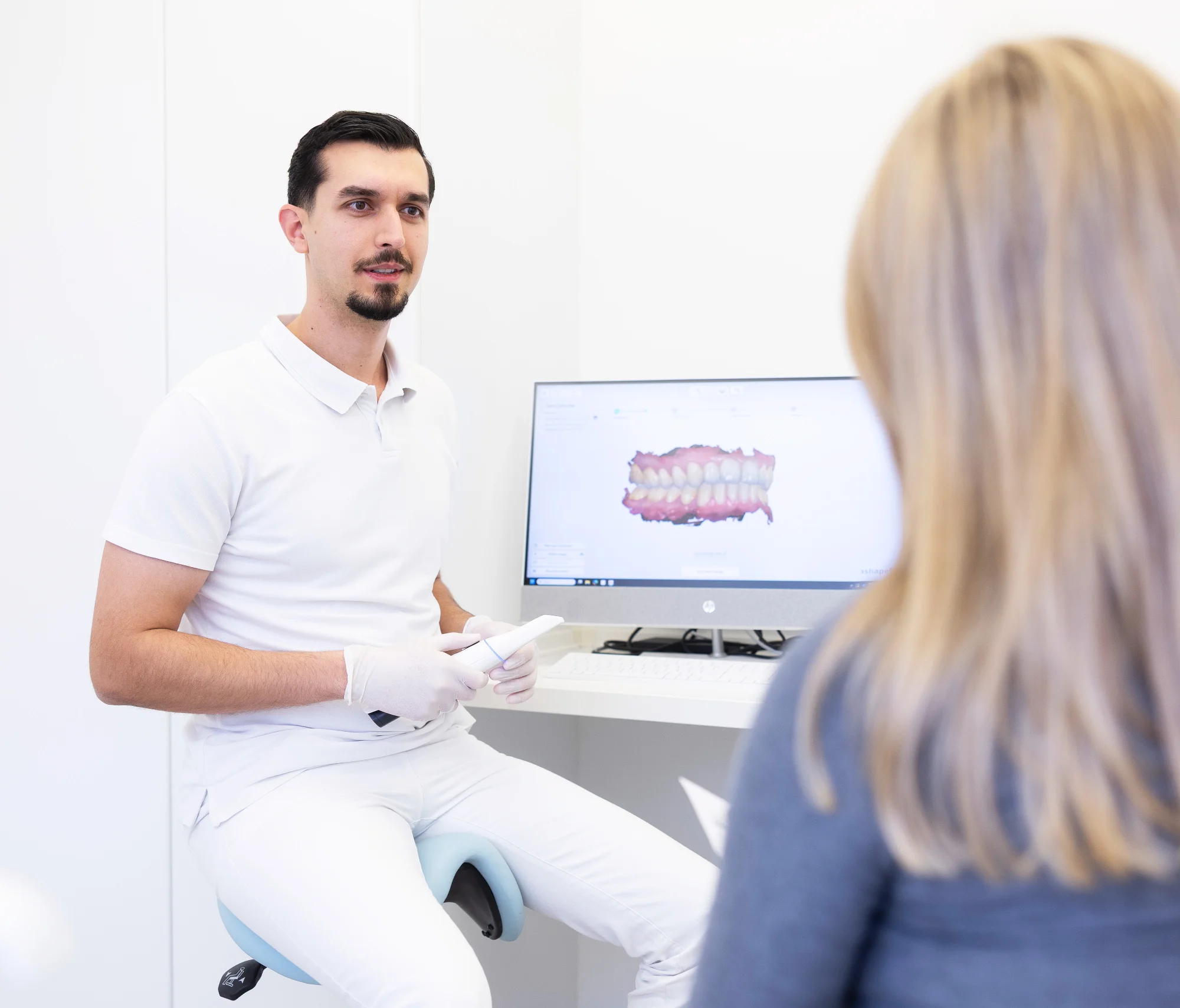 Dr. med. dent. Abazi erklärt Verbesserungen der Zähne am PC-Monitor
