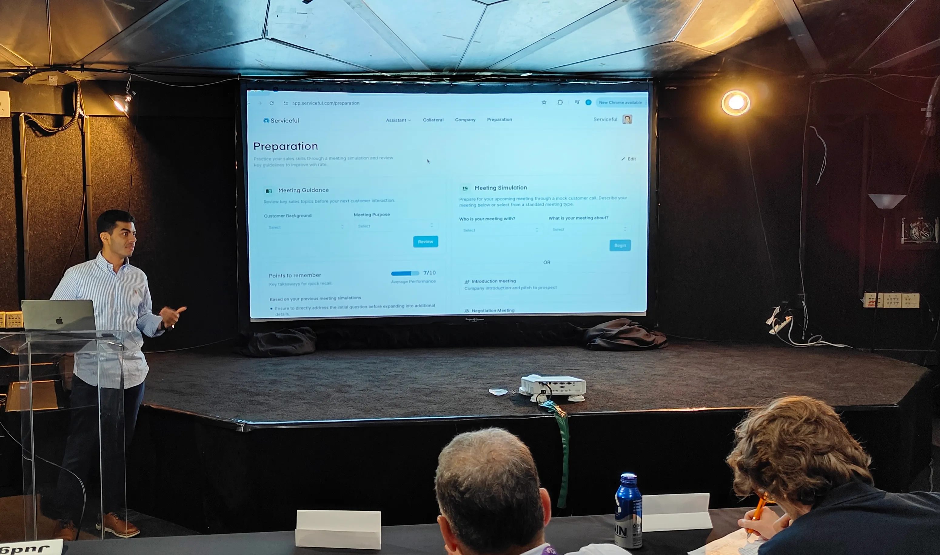 A Serviceful team member on stage demonstrating the platform's meeting preparation screen to a seated audience