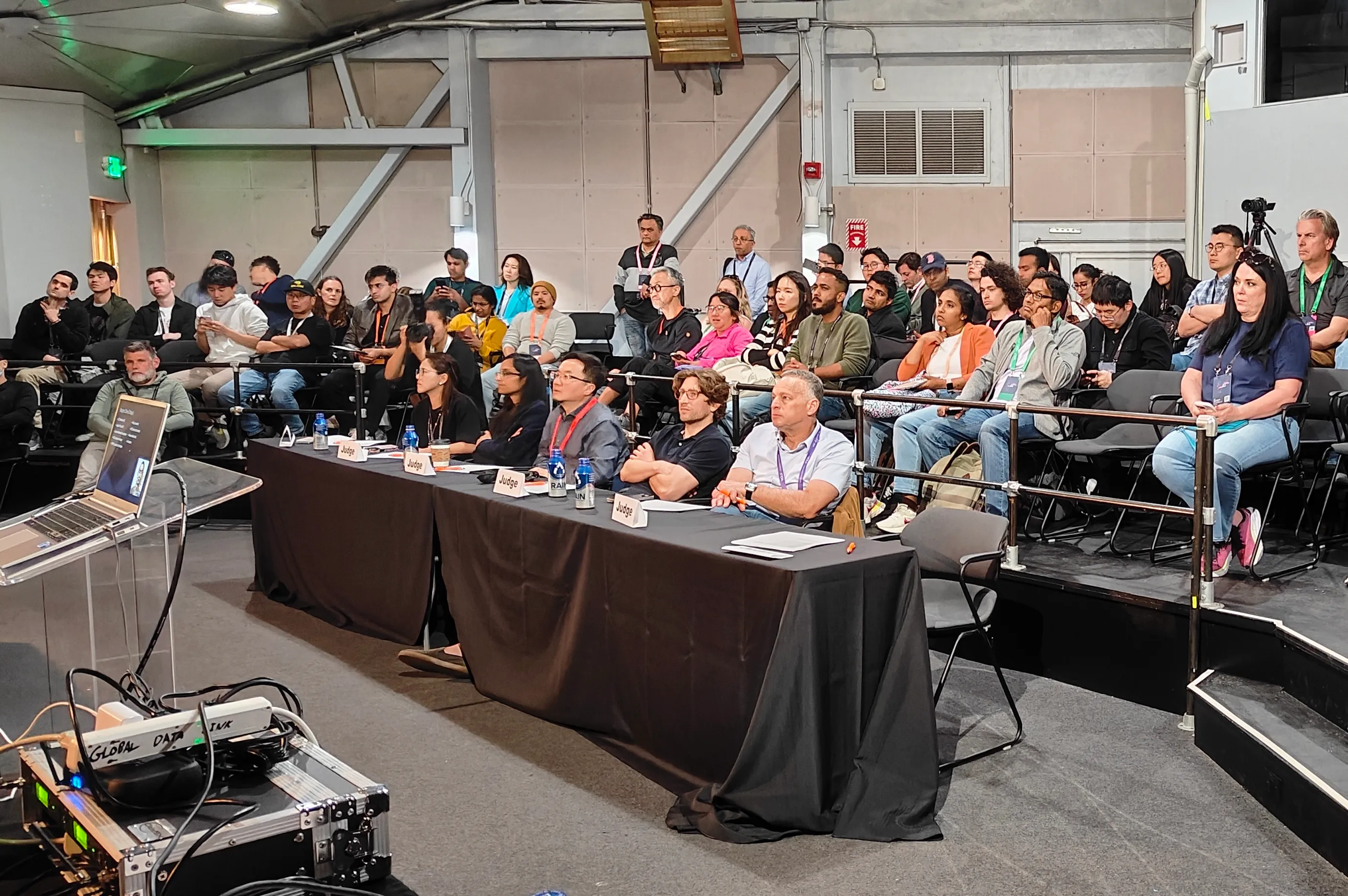 Attendees seated in a full session room facing a three-person panel at an industry event