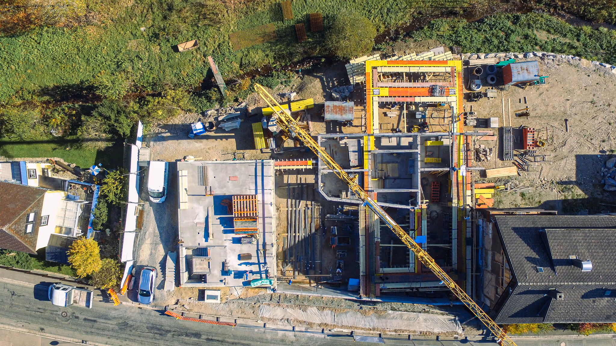 Luftaufnahme einer großen Baustelle mit Kran, Schalungen und ersten Betonarbeiten.