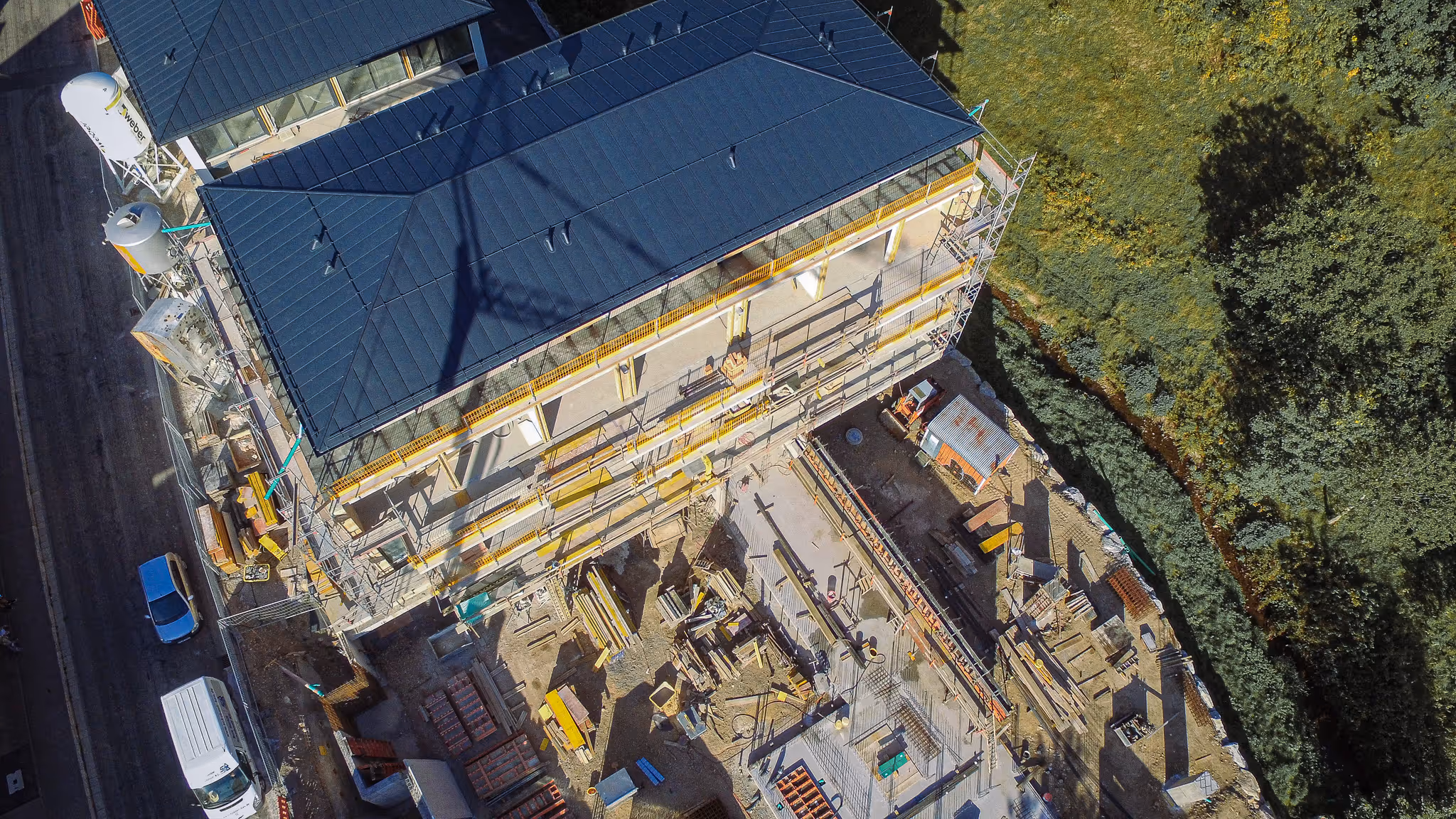 Im Bau befindliches Mehrfamilienhaus mit Gerüst. Luftaufnahme.