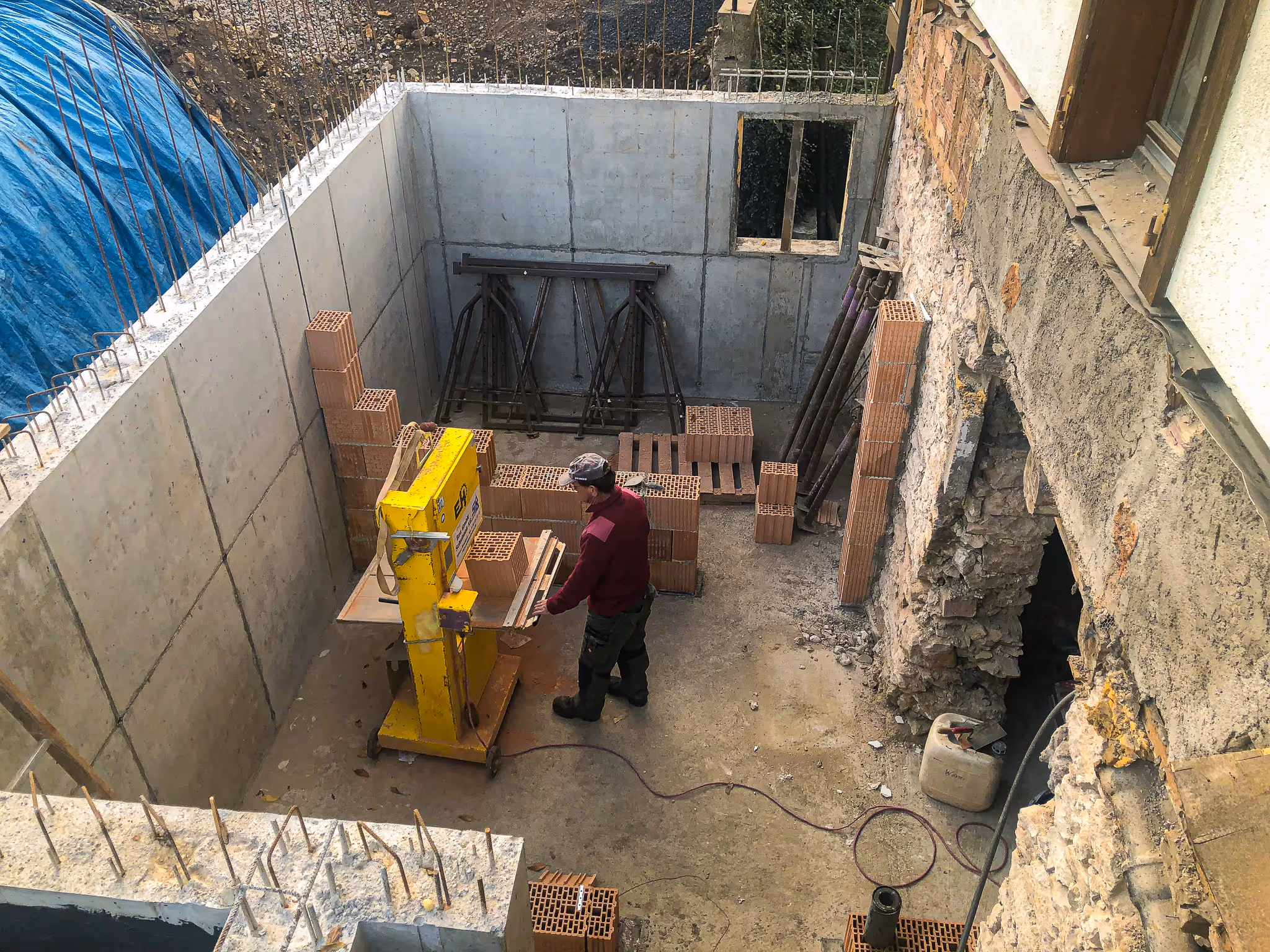 Maurer bei Steinsäge im Beton-Untergeschoss.