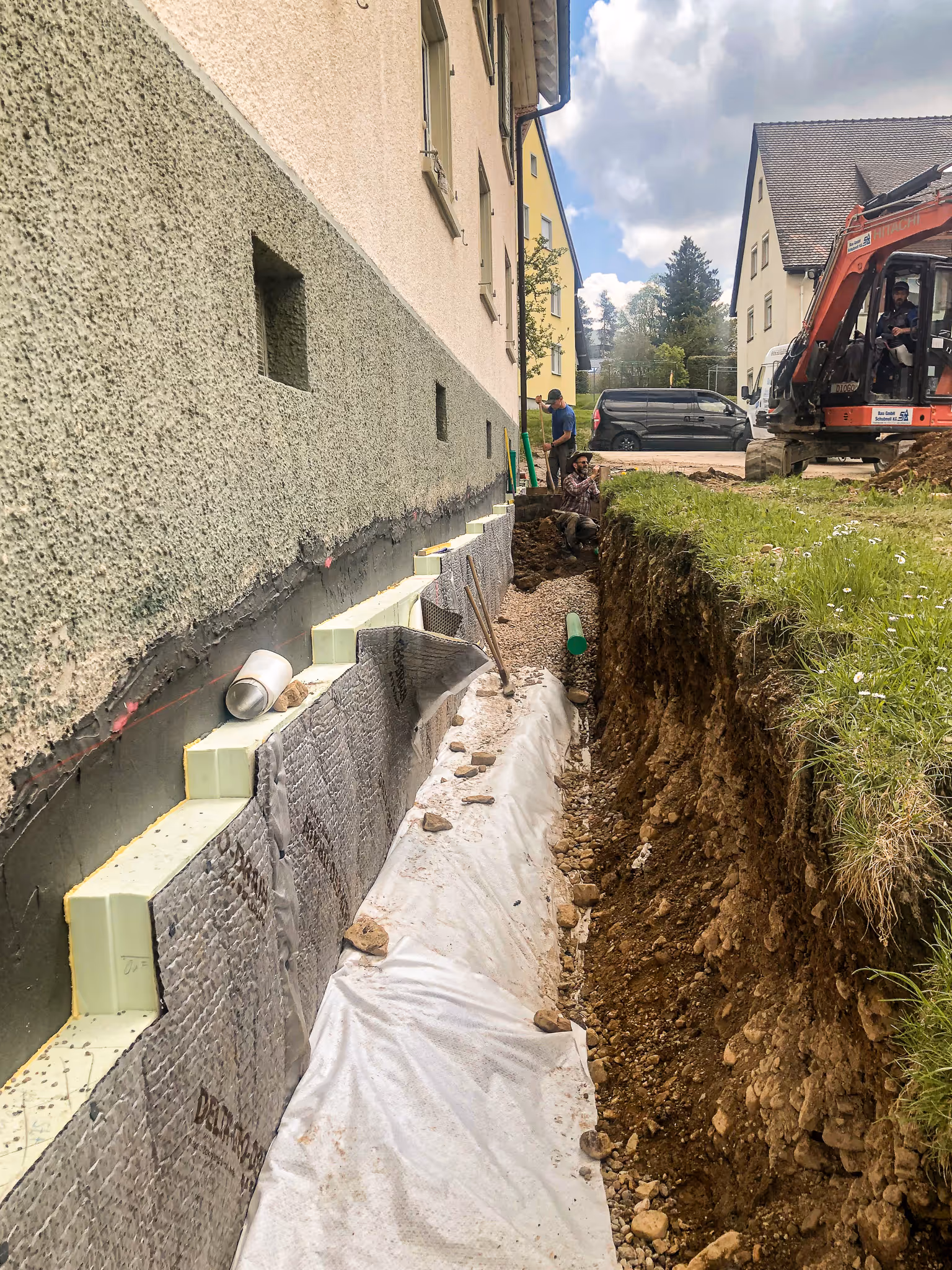 Arbeiter mit Bagger bei der Freilegung und Sanierung einer Hausfassade.
