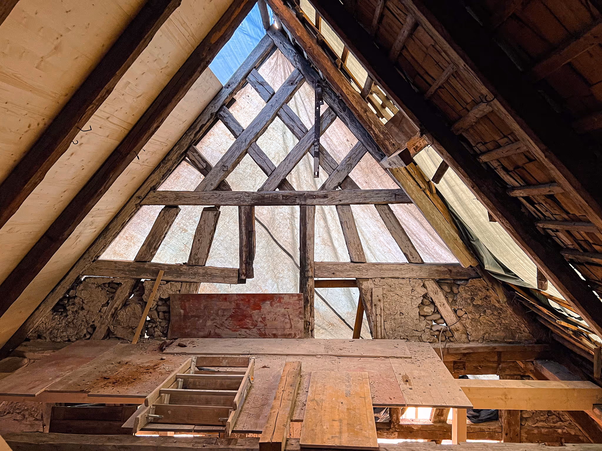 Saniertes Dachgeschoss mit freigelegtem historischen Fachwerk und Holzbalkenstruktur.