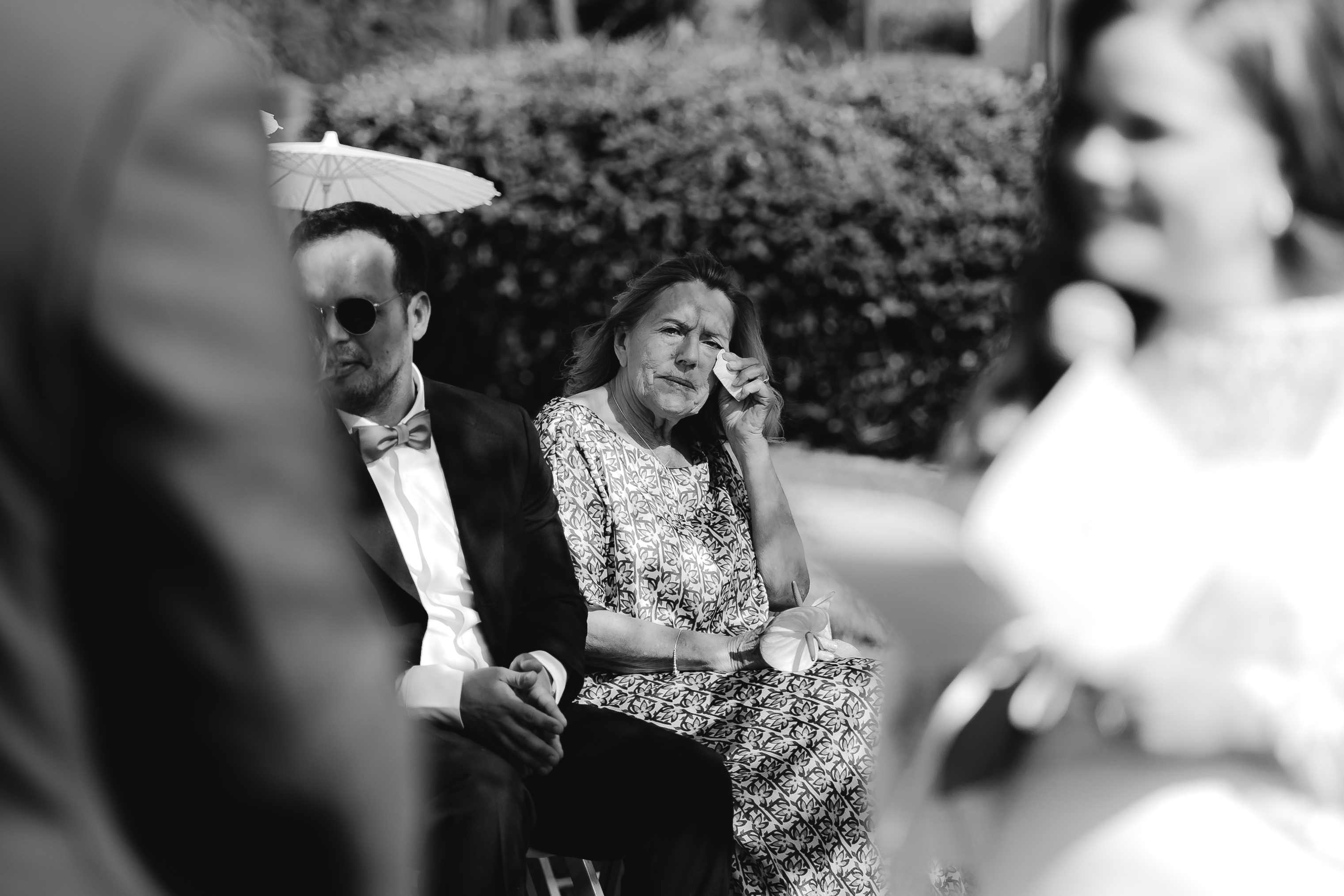 Ein Gast reagiert berührt auf Melissas Worte, zwischen dem Brautpaar hindurch fotografiert.