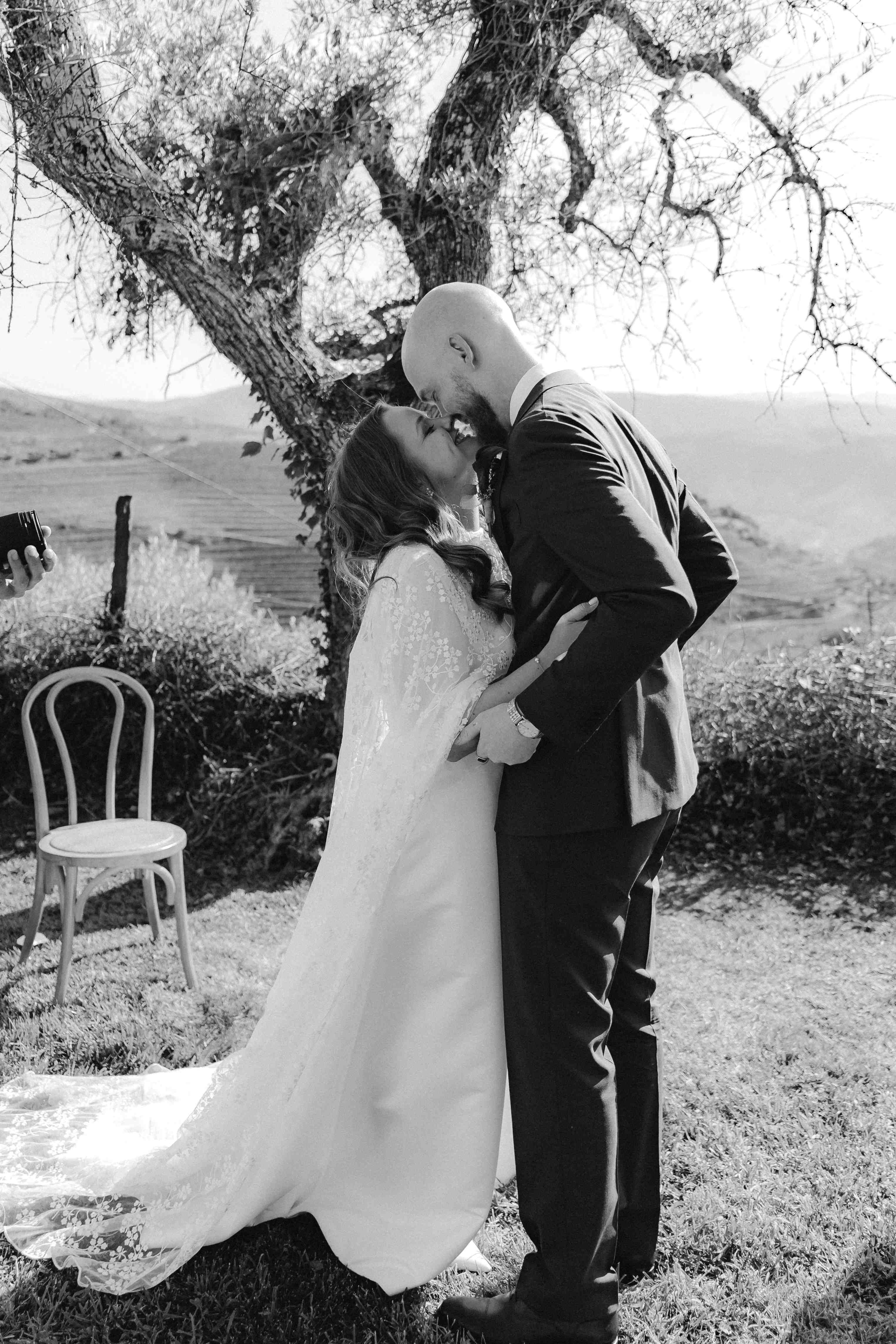 Melissa und Anders küssen sich nach dem Ja unter dem alten Baum, fotografiert in Schwarzweiß.