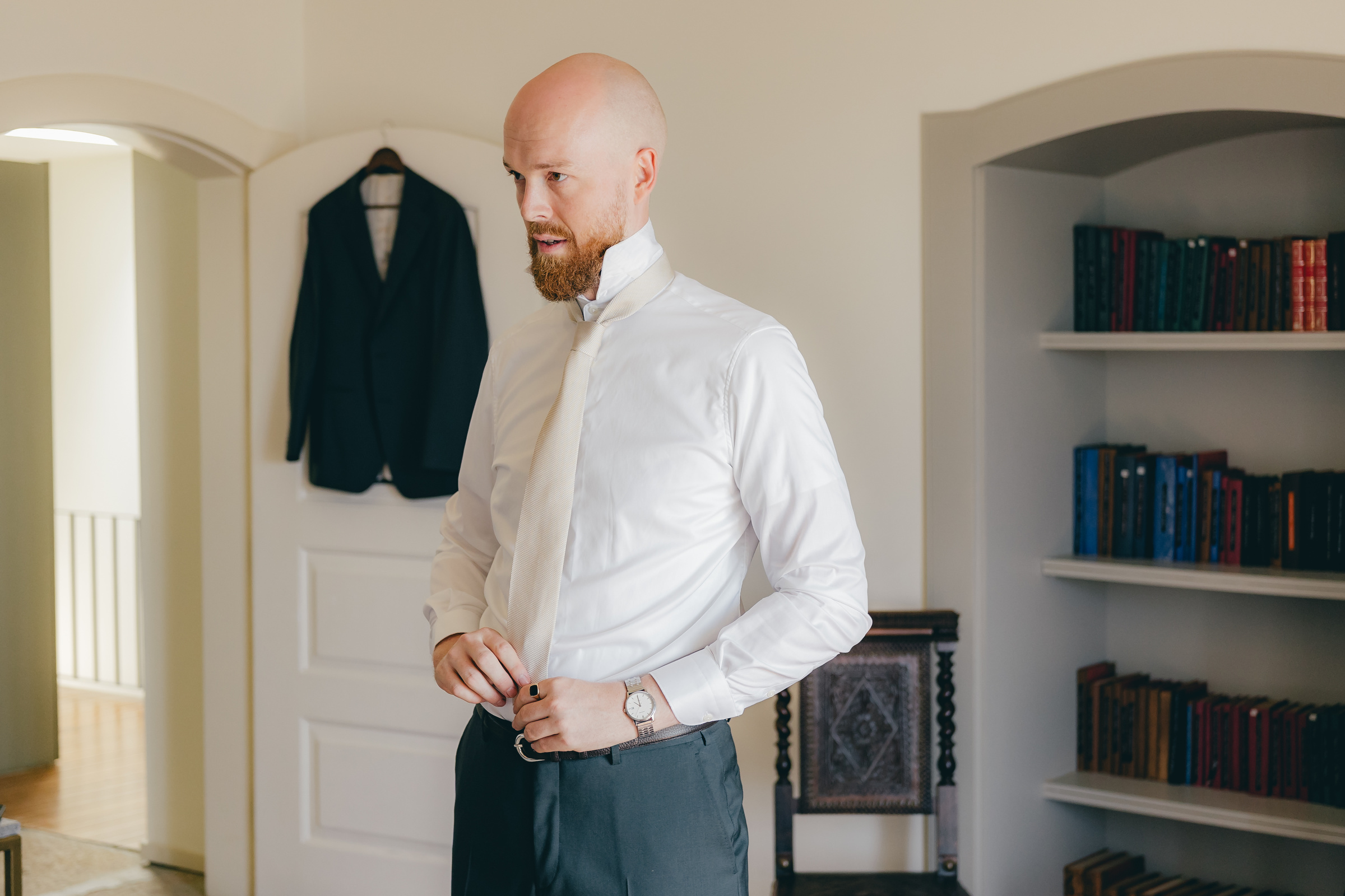 Anders richtet Hemd und Hose vor der Zimmerwand mit Bücherregal und aufgehängtem Jackett