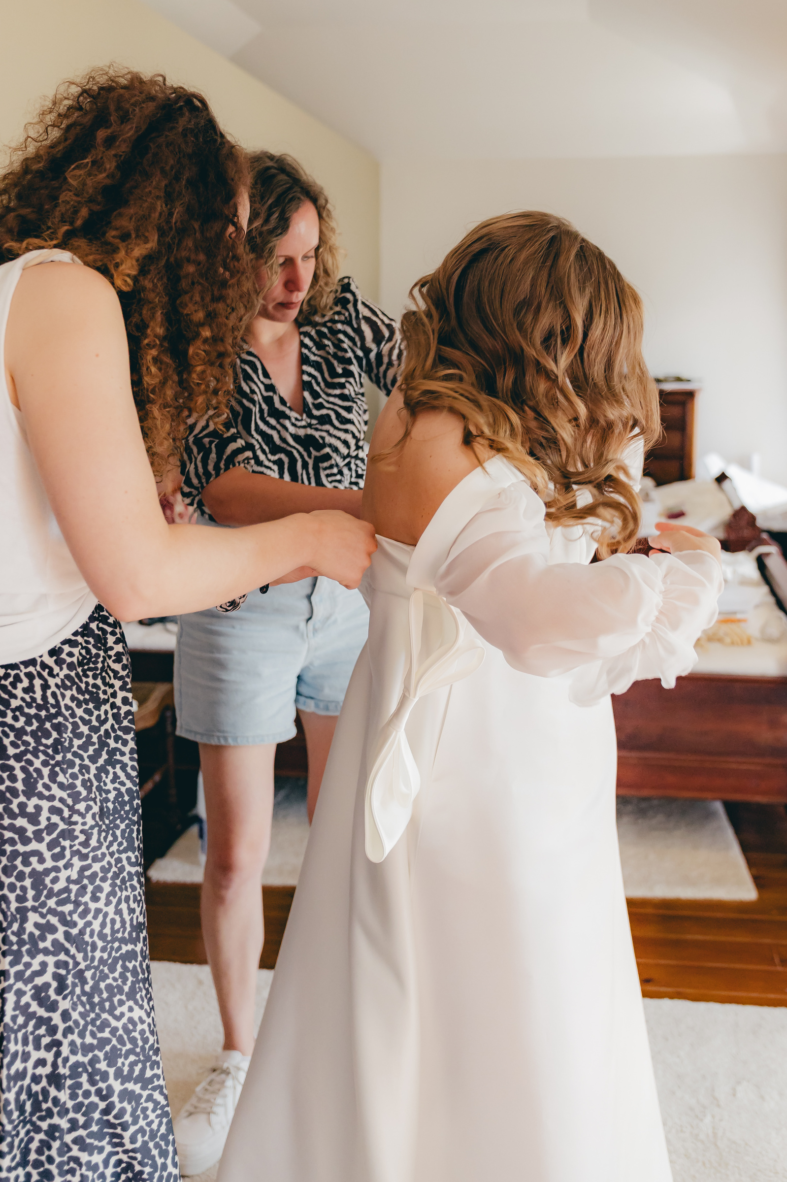 Freundinnen helfen Melissa beim Anziehen ihres Brautkleides.