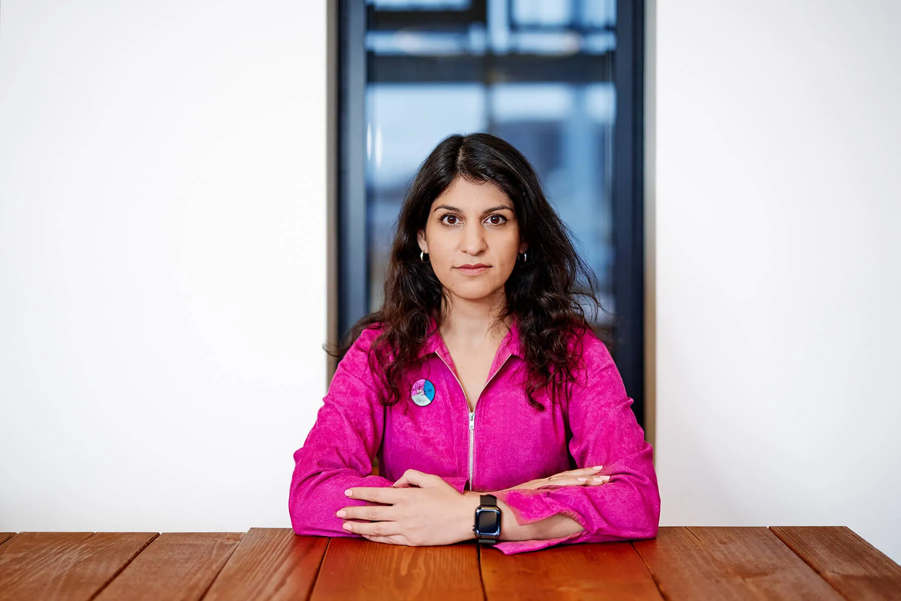 Zamina Ahmad sitzt am Tisch, Blick in die Kamera.