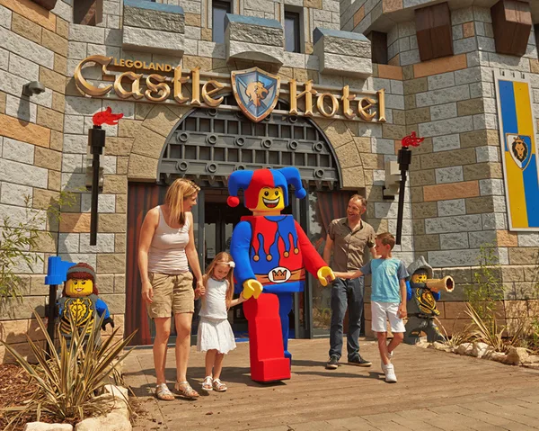 Photo of the exterior of the LEGO castle hotel with a LEGO figure in the middle walking in a line with two children, mother and father