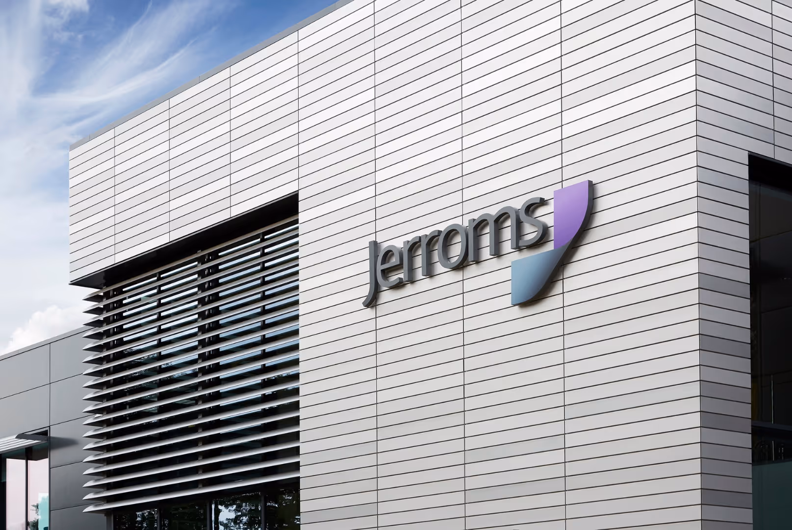 Modern building exterior with horizontal white paneling and a sign reading 'Jerroms' next to a blue and purple logo.