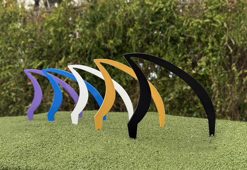 Tee colors black golf white blue and purple- cut aluminum tee markers arranged in a row on green grass.