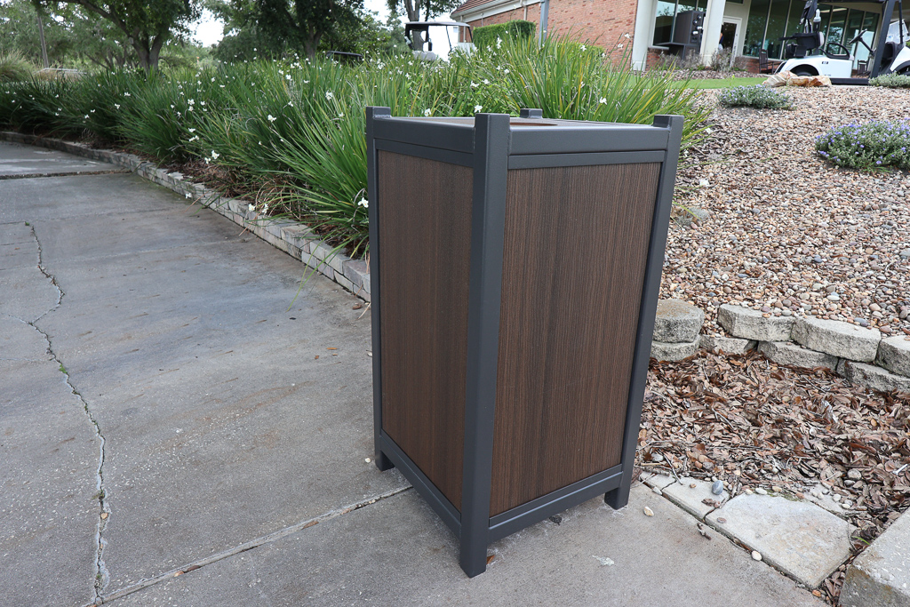 outdoor trash can with dark brown wood panels and dark frame outside the driving range.