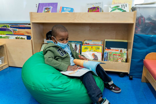 Student reading a book on green bean bag chair
