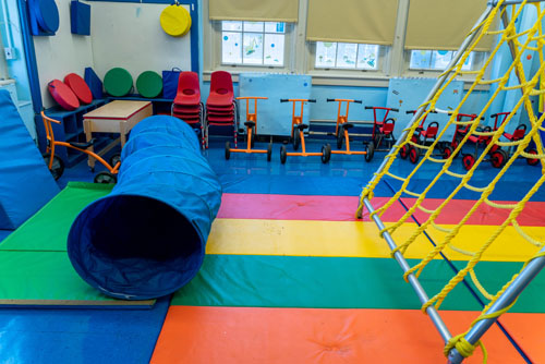 Colorful indoor play area with tunnel climbing frame and tricycles
