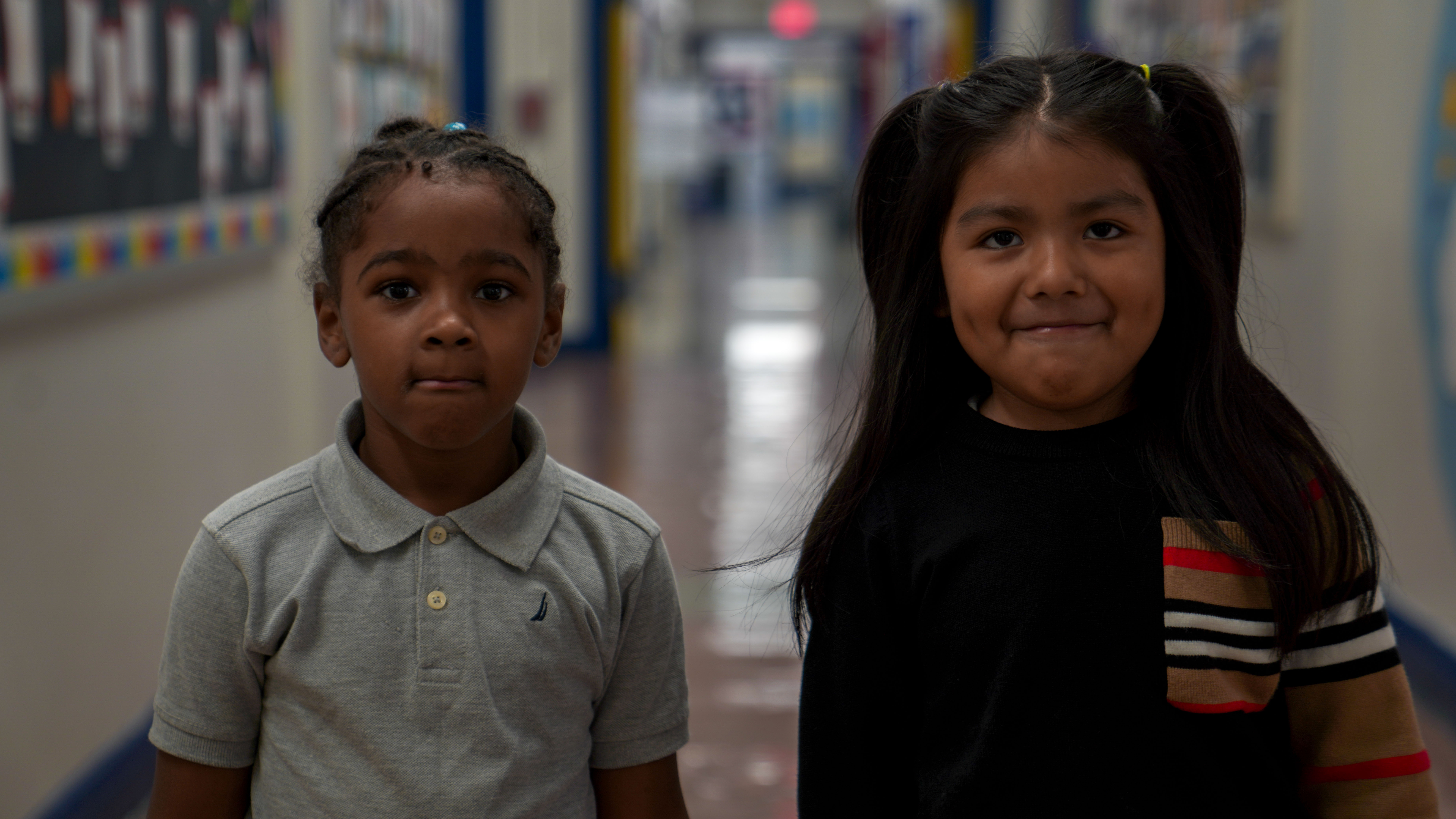 Two elementary students standing together in a school hallway
