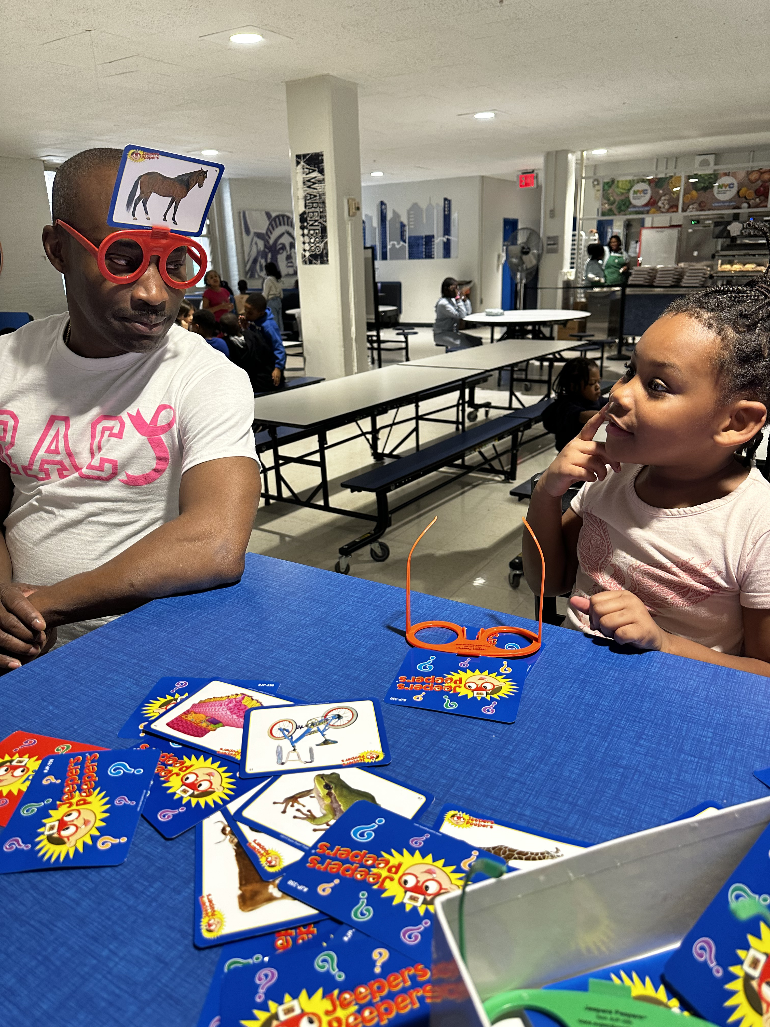 Adult and student playing Jeepers Peepers guessing game in cafeteria