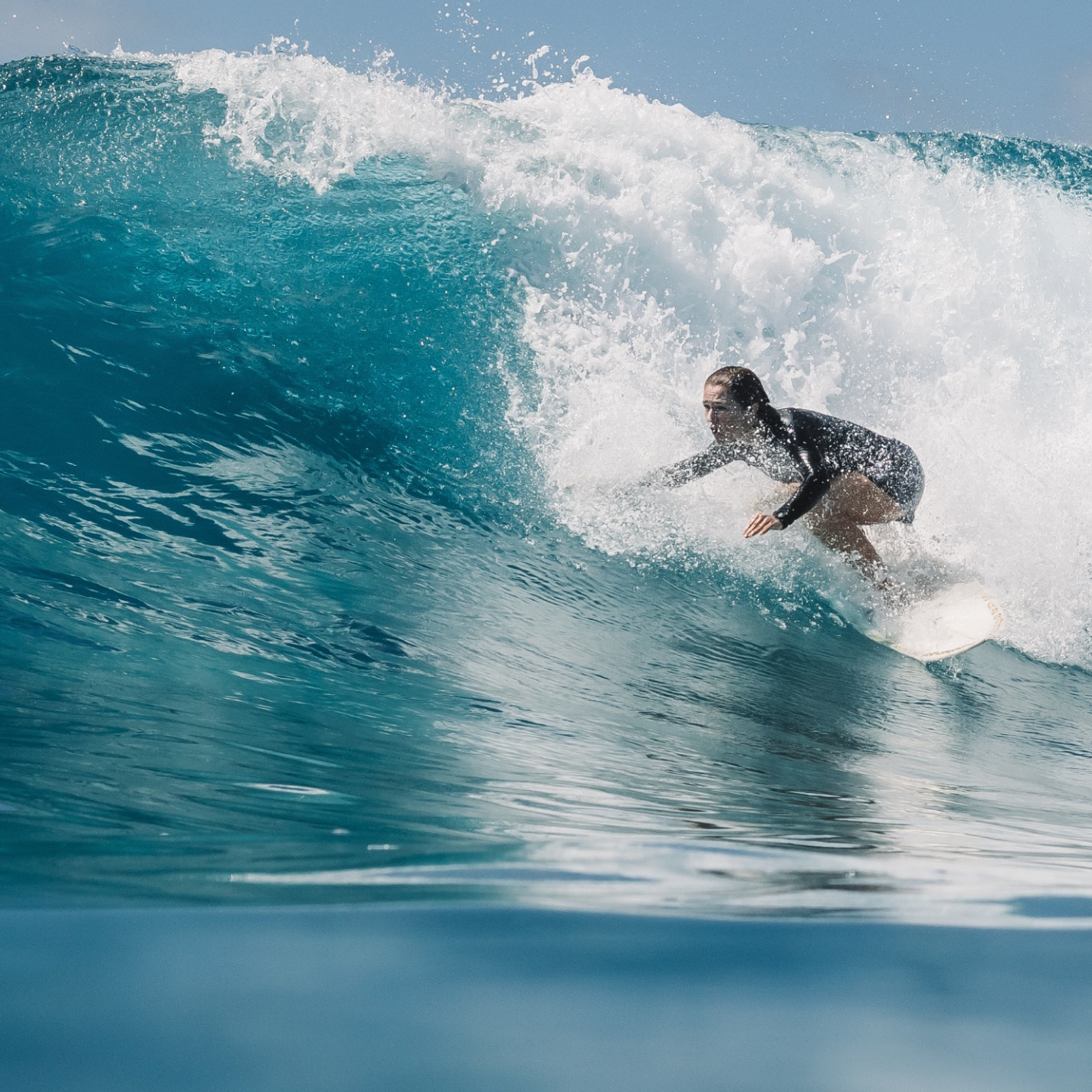 A photo of a woman surfing a tropical wave