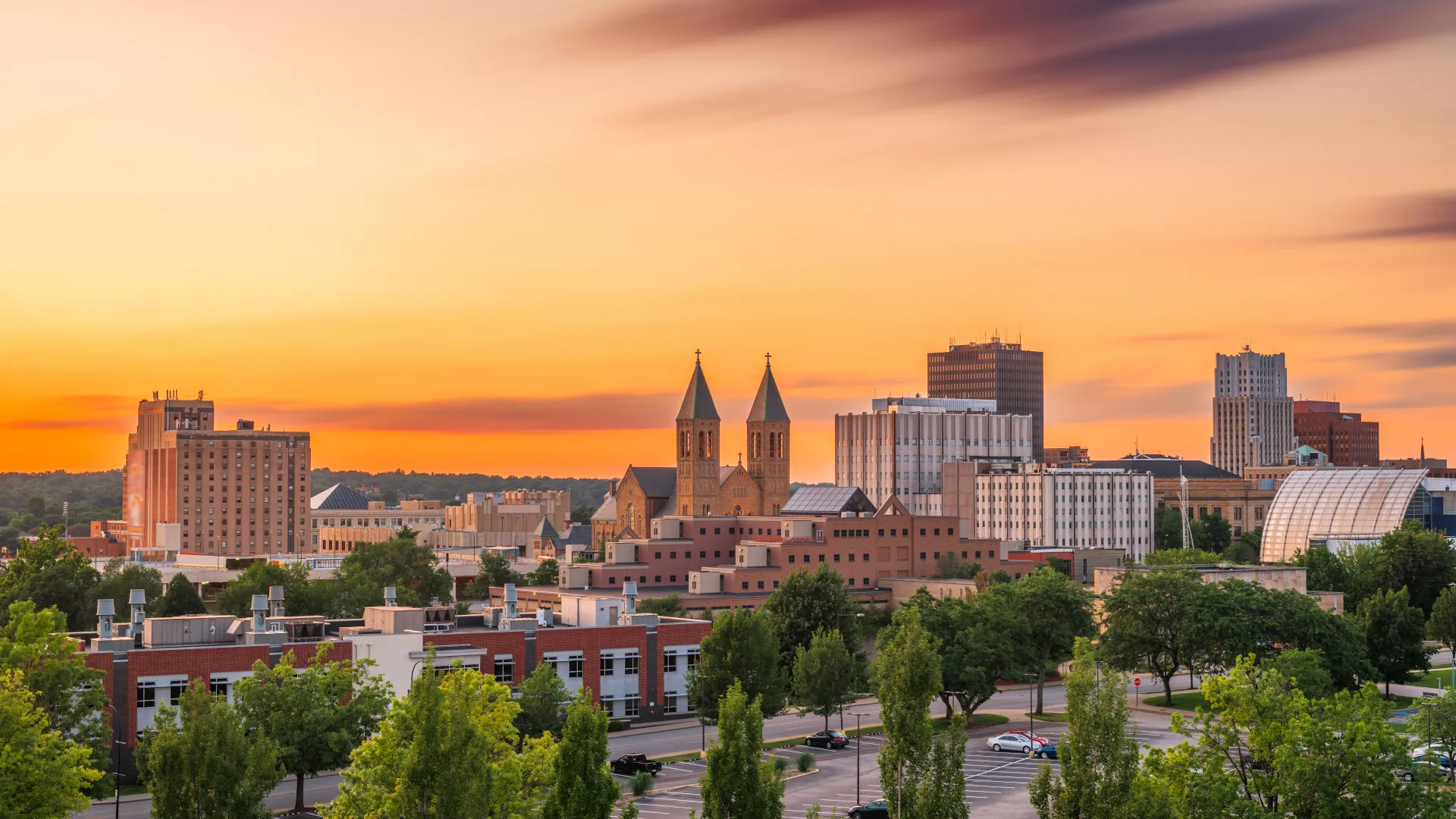 Downtown Akron, Ohio skyline at sunset with church towers and various buildings.