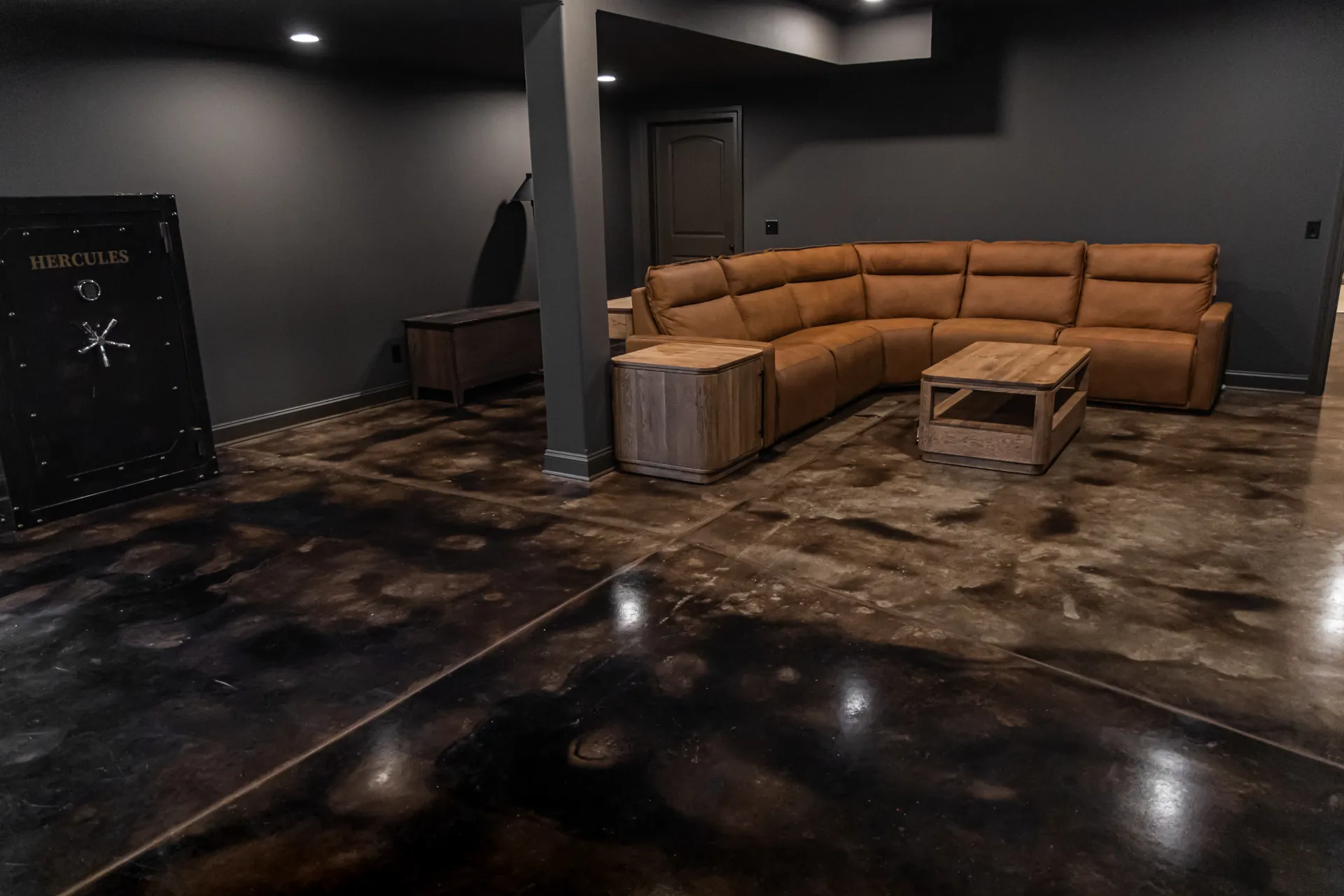 Finished basement featuring a custom acid stained concrete floor with rich brown and black marbled tones, decorative saw-cut scoring, and a high-gloss protective finish.