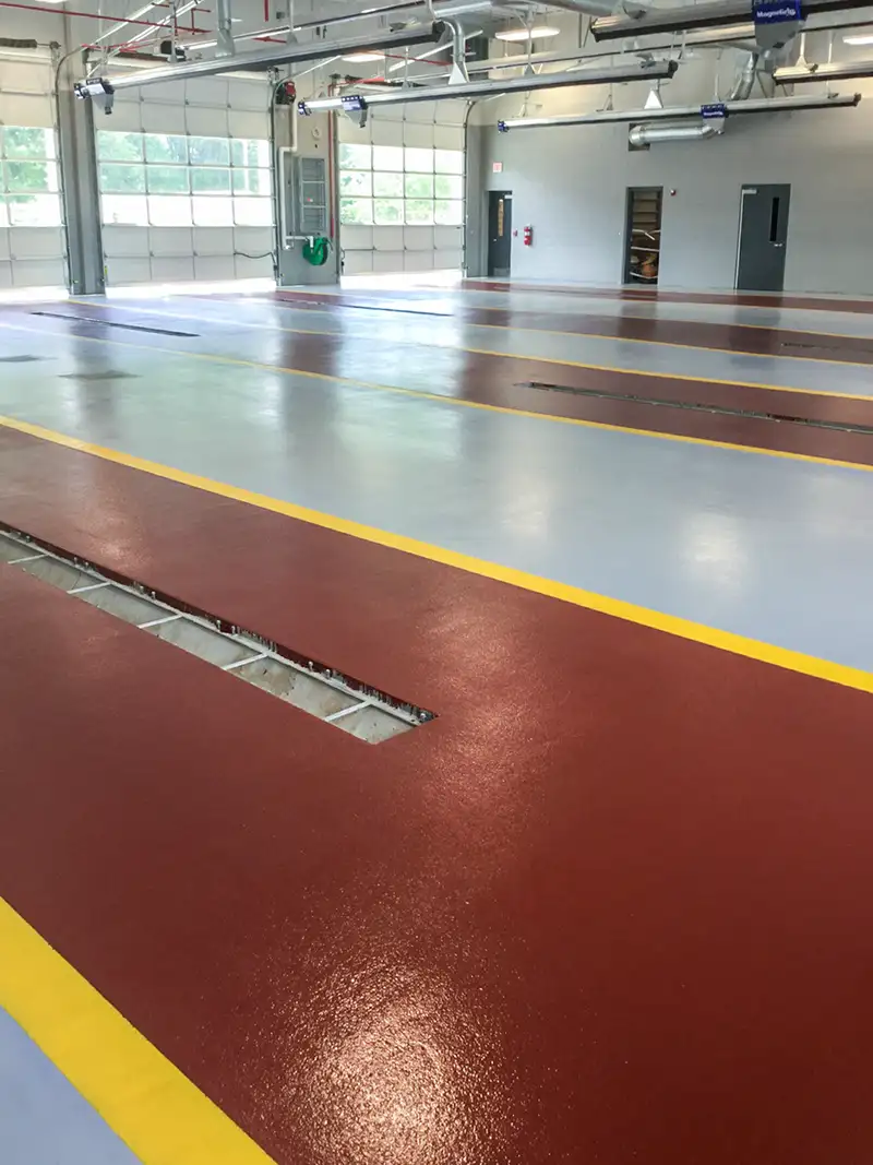 Empty fire station garage with shiny red and gray Urethane cement floors marked by yellow lines.