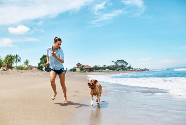 person running on the beach with a dog