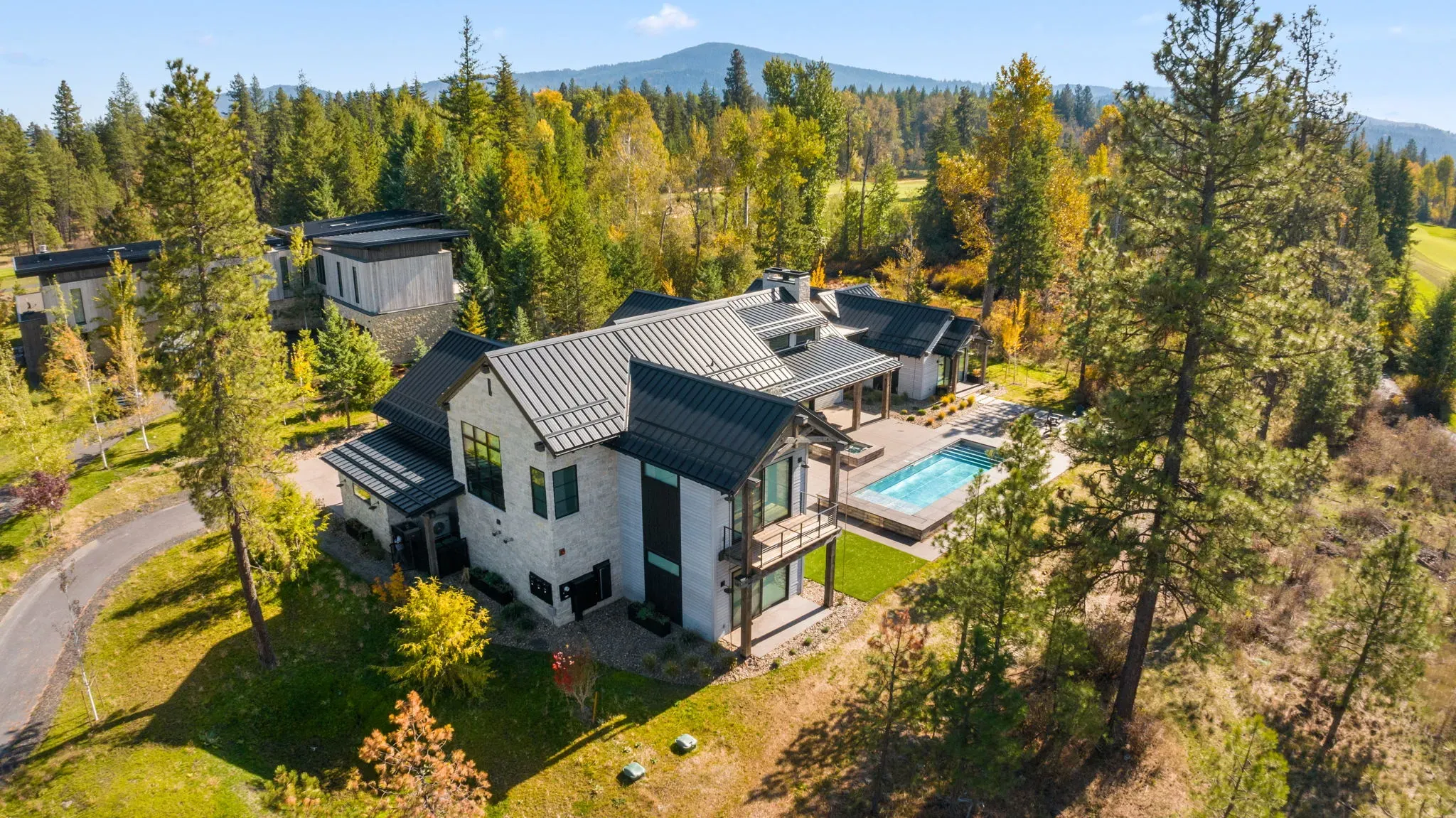 Aerial view of a custom home with pool surrounded by pines, built by StanCraft Construction Group in North Idaho