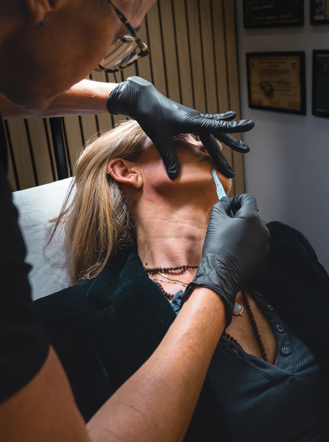 Two women standing on a city sidewalk, one wearing headphones and holding a MANGO shopping bag while looking at her phone, the other wearing glasses and a black dress.