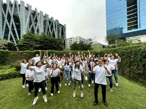 Energetic group photo of people joyfully jumping together on a grassy field.