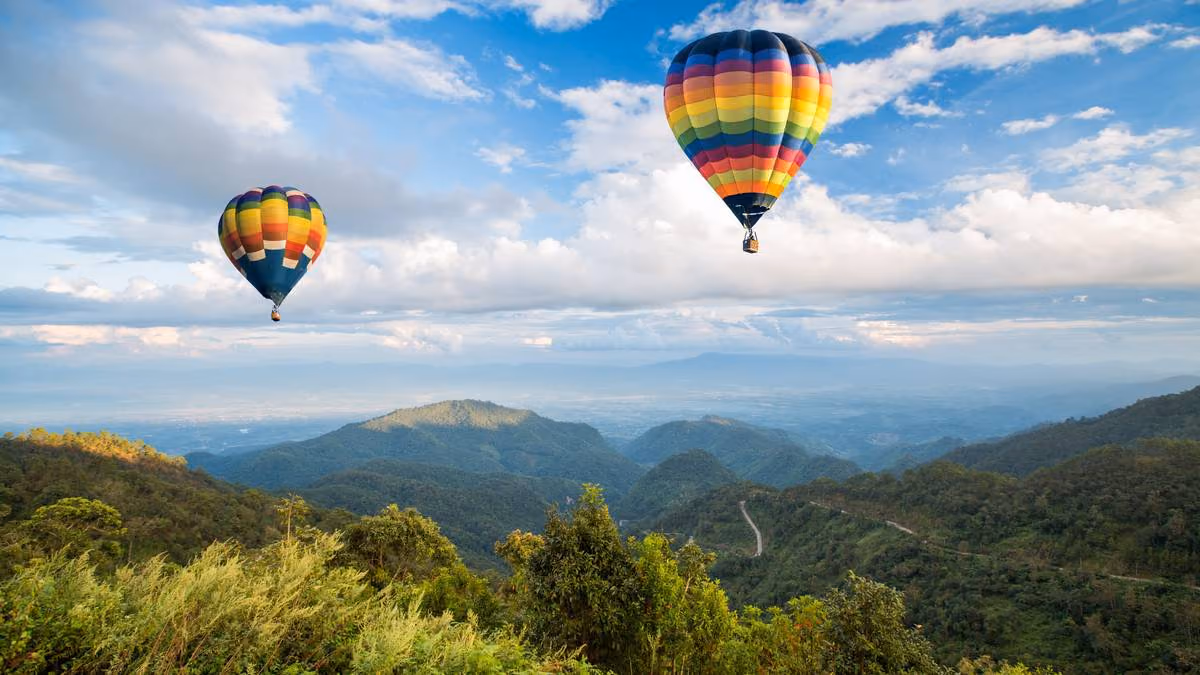 A colorful hot air balloon floating above the Manyeleti Game Reserve at sunrise, offering passengers a bird's-eye view of the landscape.