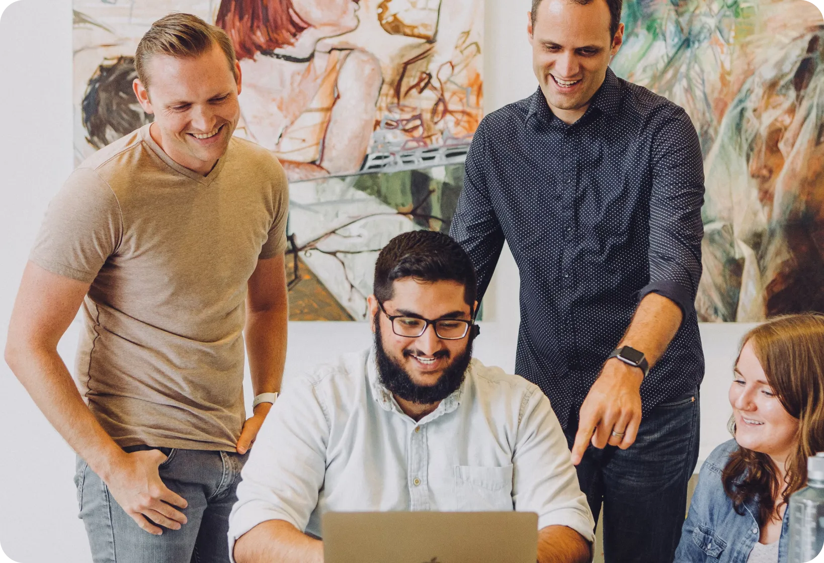 A group of men standing around a laptop computer.