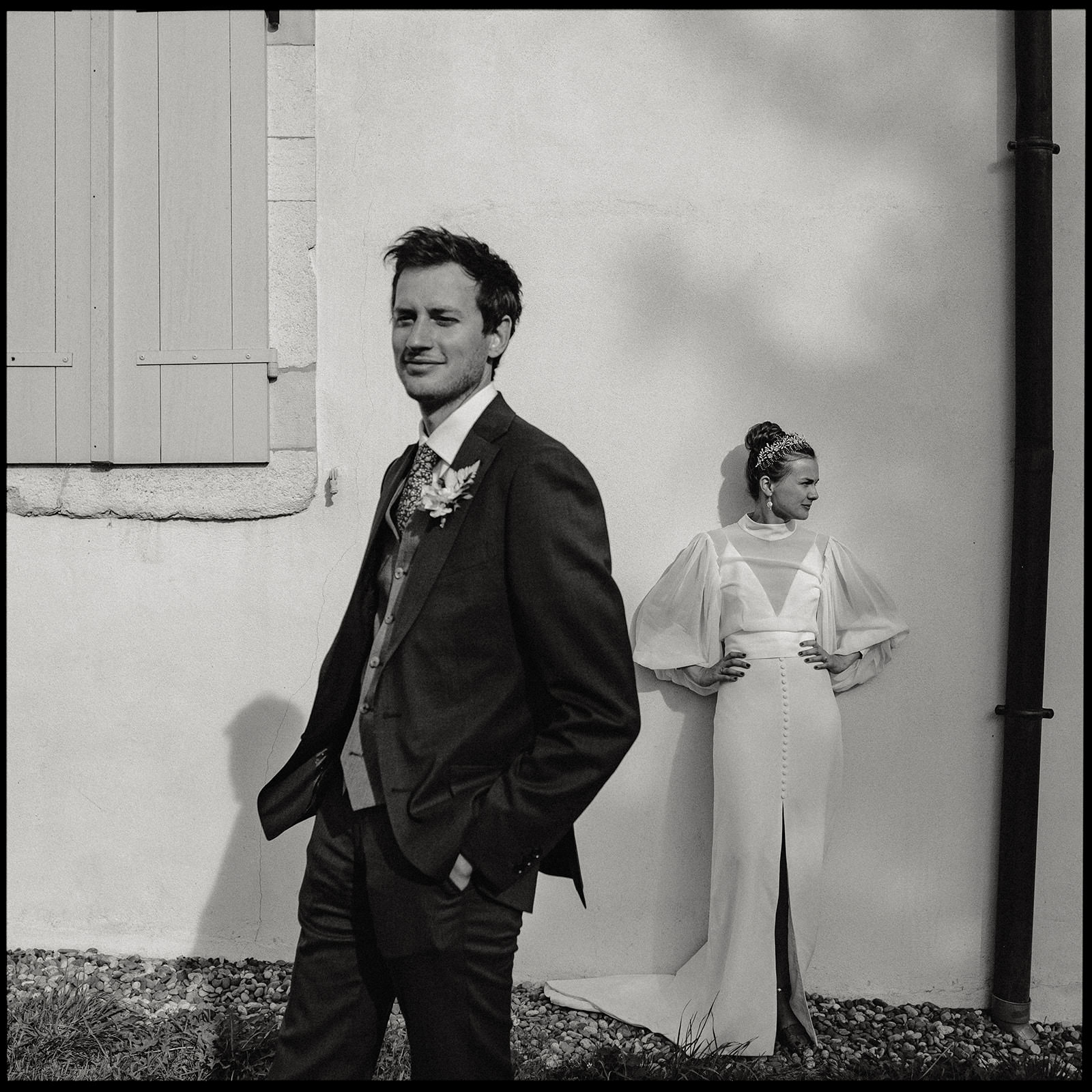 Black and white portrait of a bride and groom outside a stone house