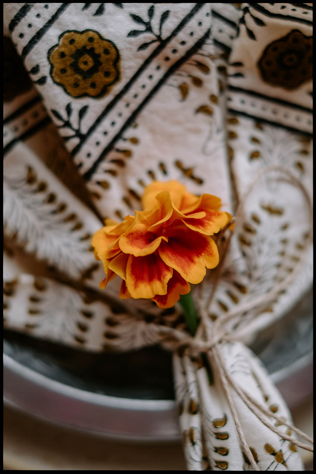 Orange marigold tucked into a patterned napkin