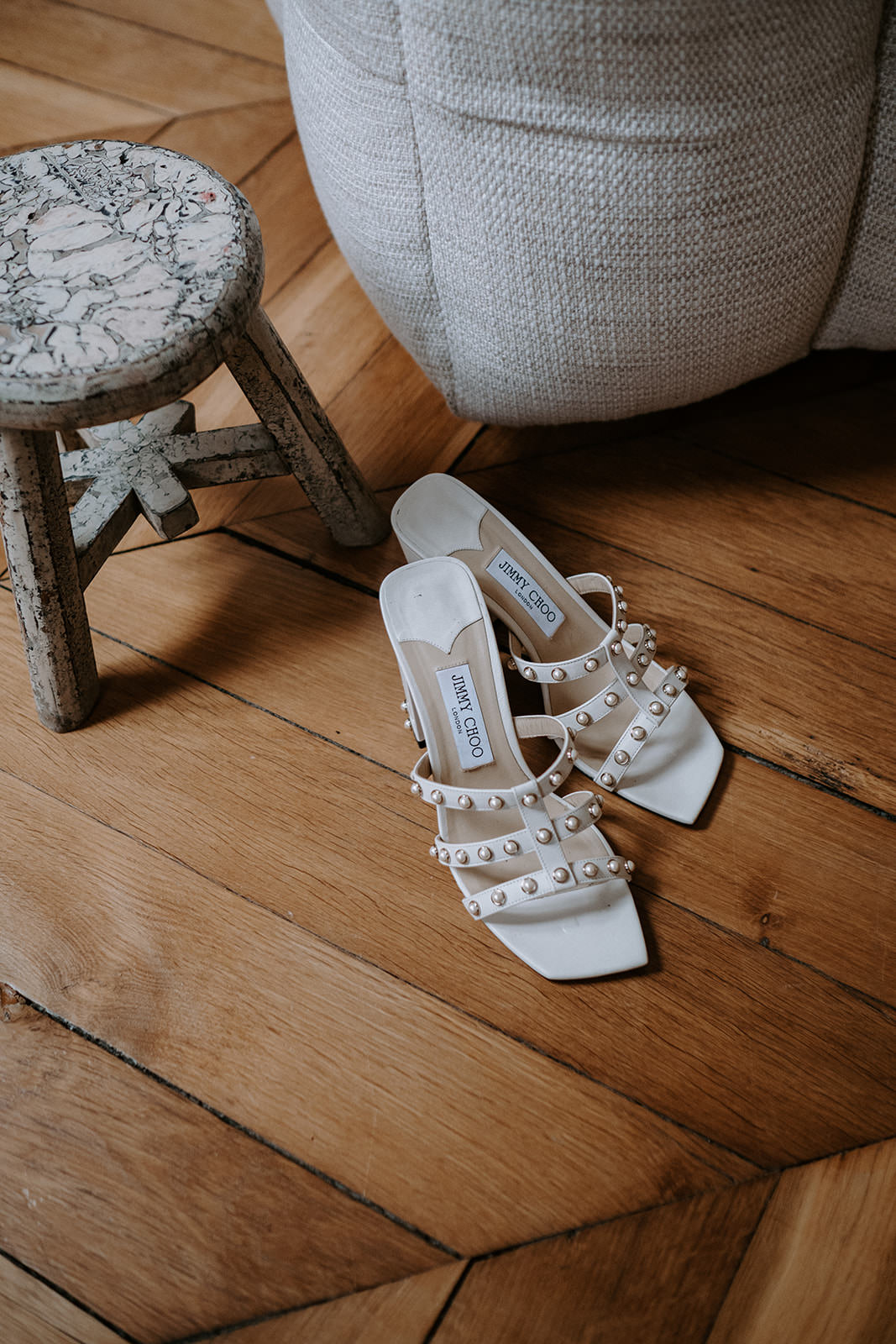 Bride's studded white sandals on a wooden parquet floor