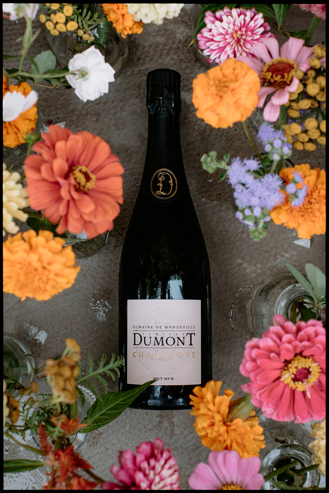 Bottle of champagne surrounded by colourful flowers