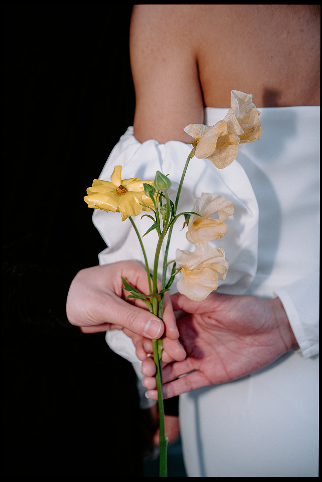 Bride in a white sleeve holding delicate yellow flowers
