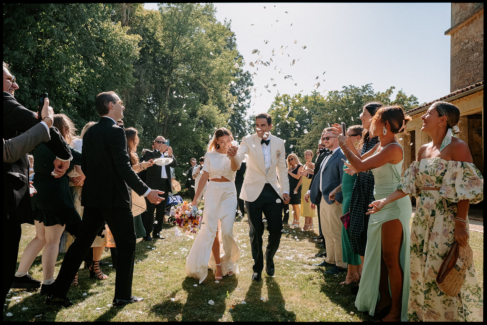 Bride and groom walking through guests throwing confetti