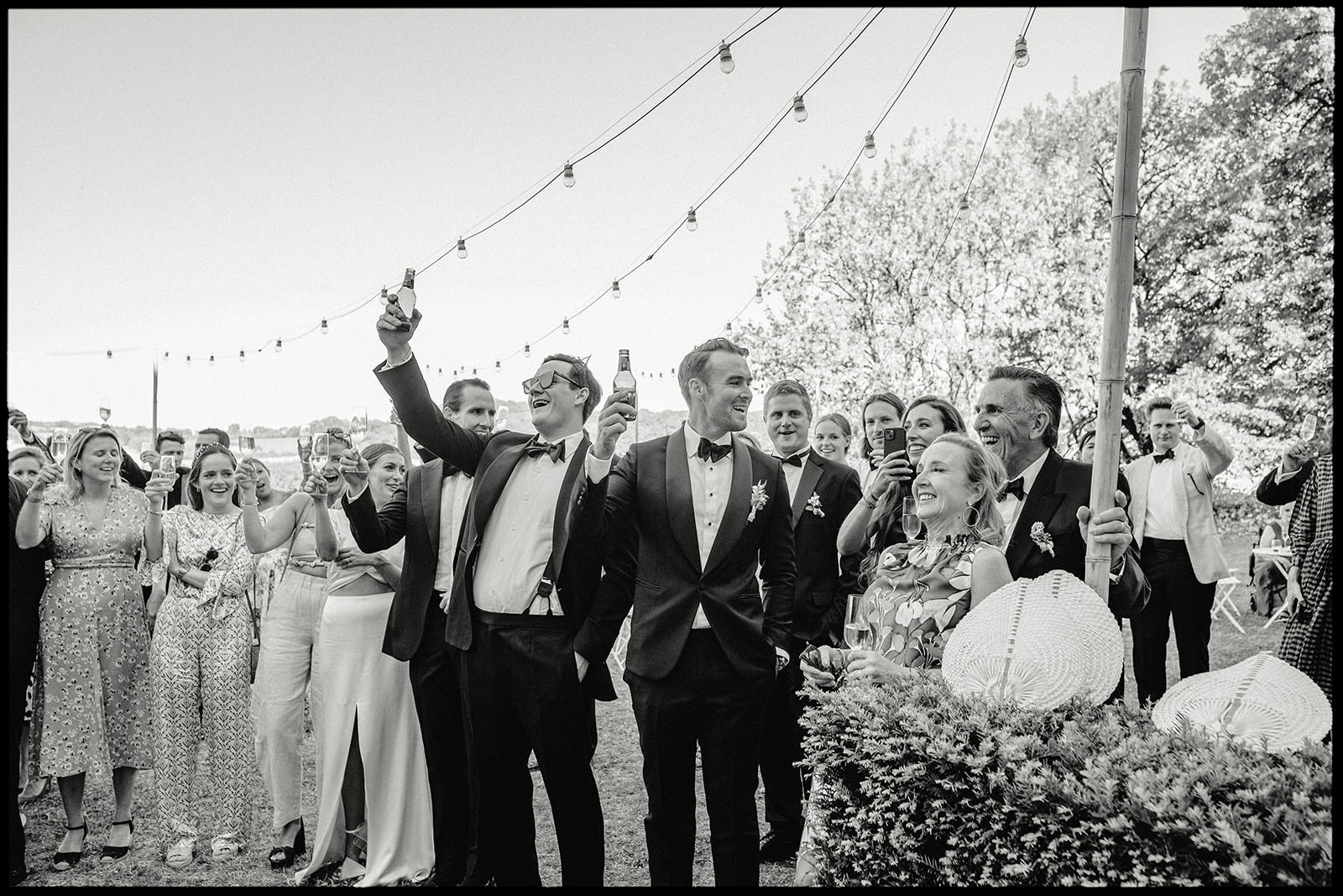 Black and white photo of guests celebrating under string lights