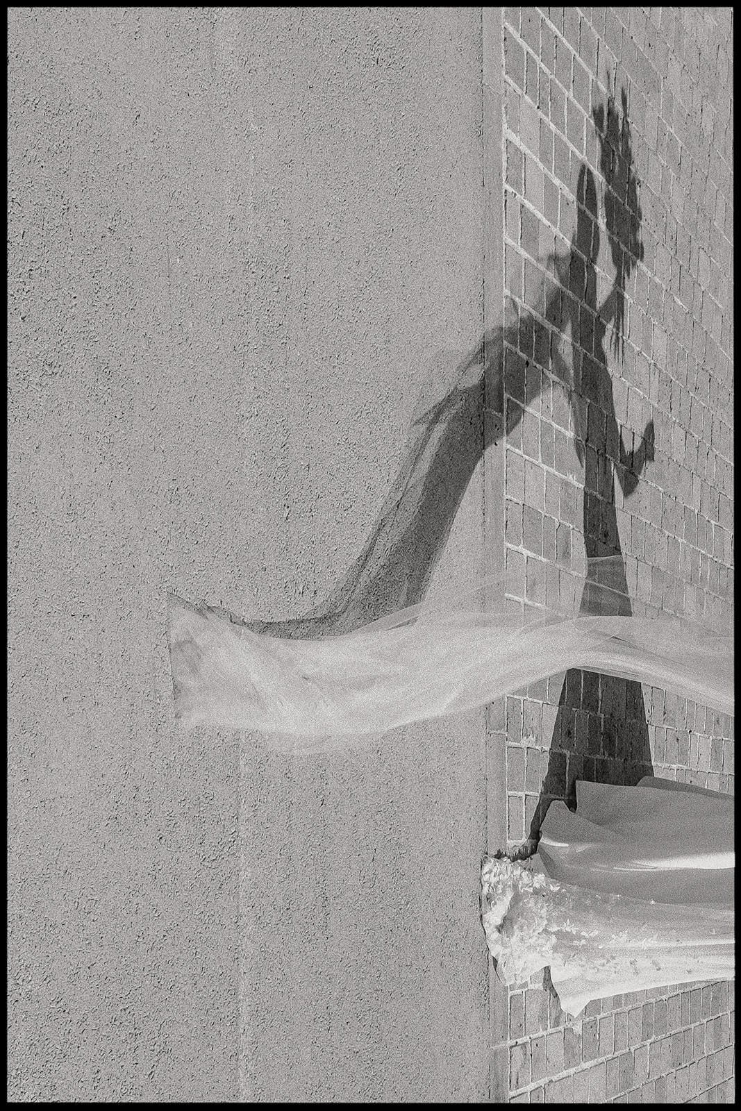 Bride's veil flying in the wind beside a stone wall