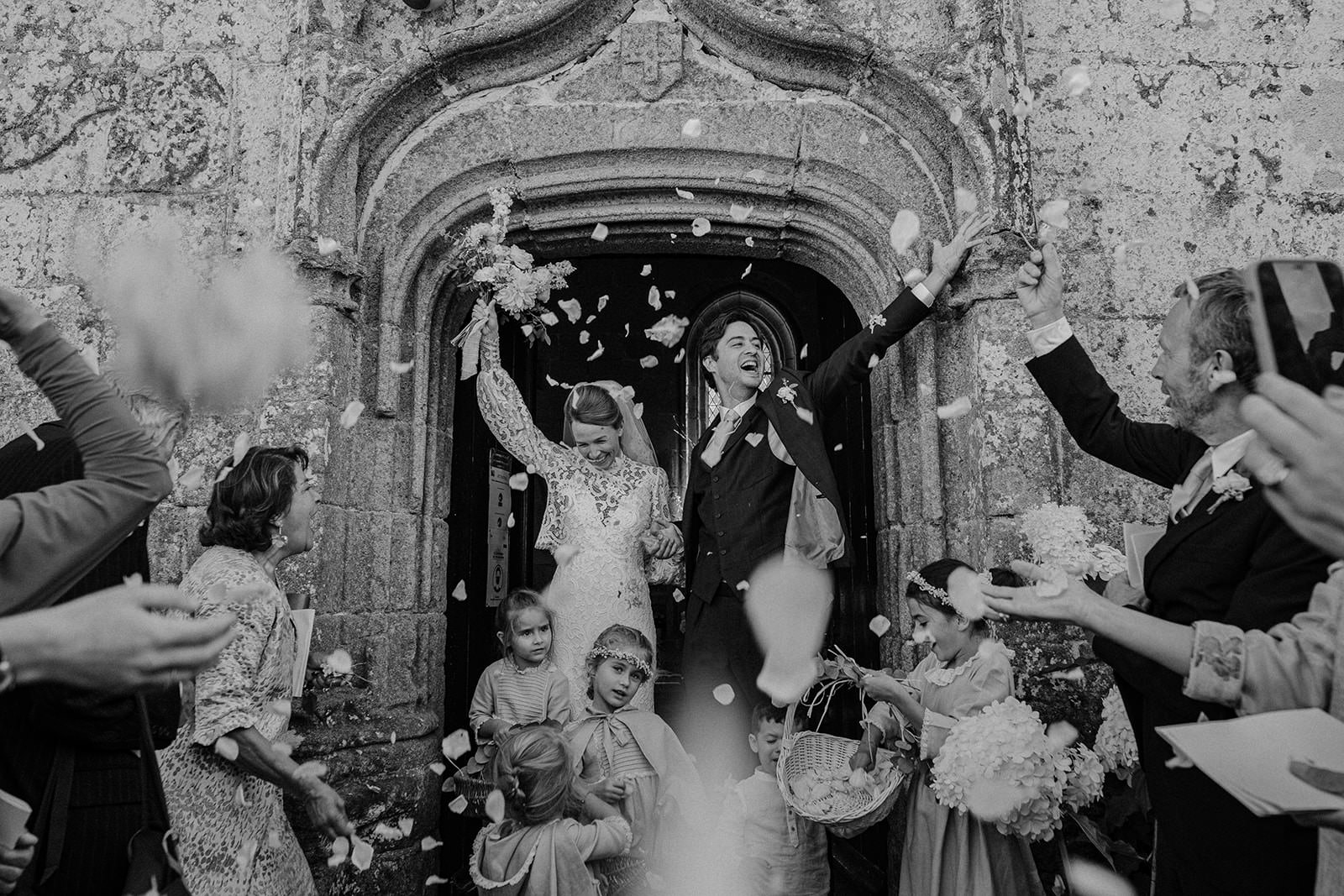 Black and white photo of guests throwing petals as the couple leaves the church
