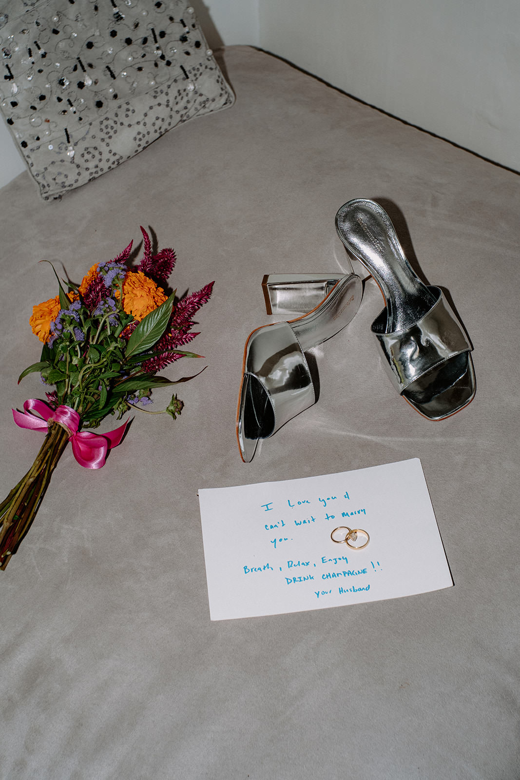 Bridal shoes, bouquet and a handwritten note on a bed