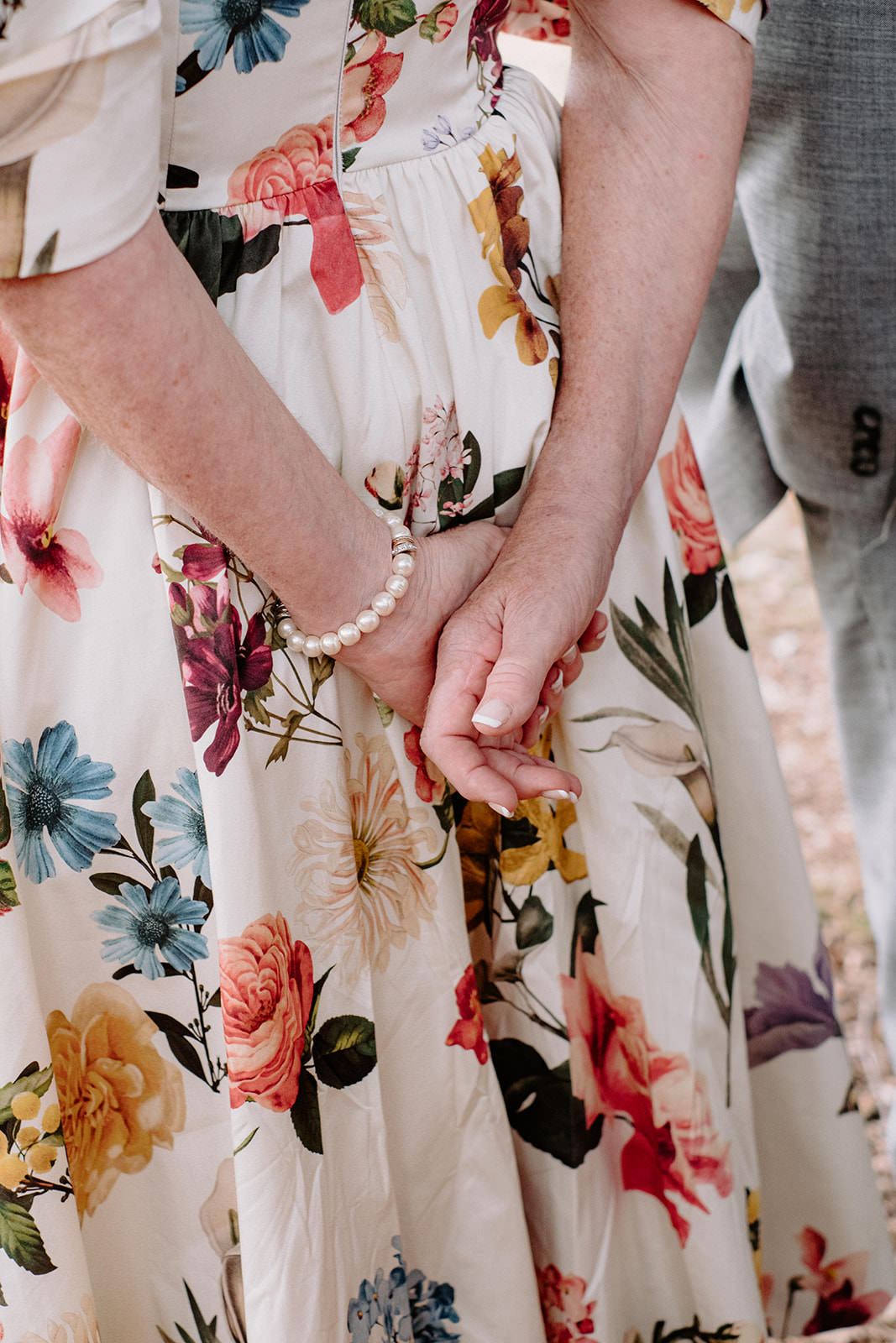 Wedding guest in a floral dress with a pearl bracelet