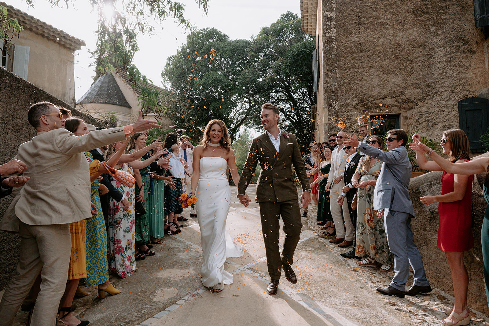 Bride and groom walking through cheering guests in a village street