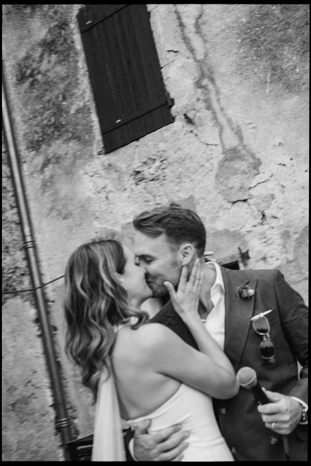 Black and white photo of a couple kissing in a village street