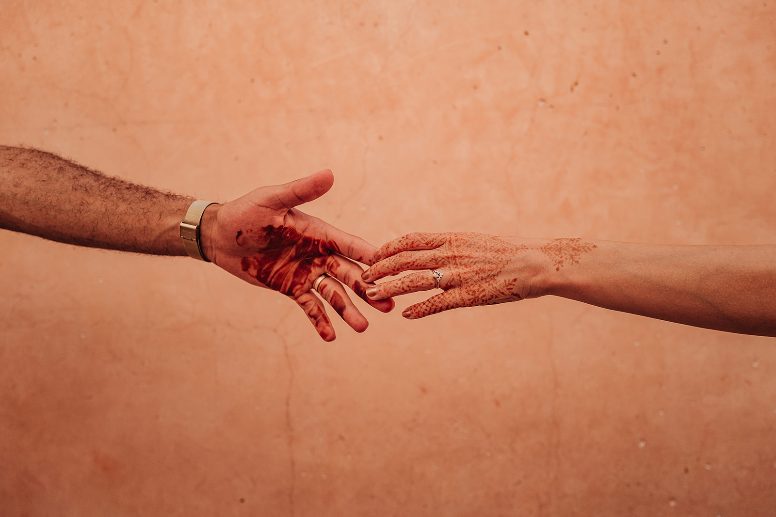 Two hands reaching for each other against a warm orange wall