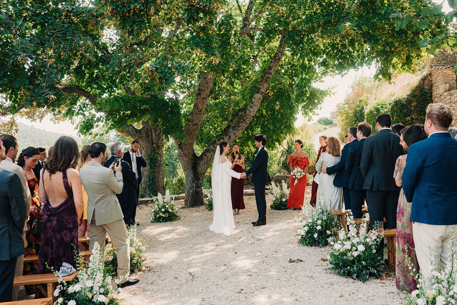 Bride and groom walking out through cheering guests after their wedding ceremony in a Provence village