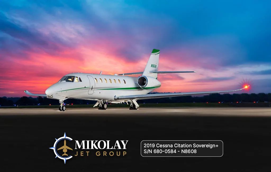 2019 Cessna Citation Sovereign+ S/N 680-0584 - exterior of white and green gray striped aircraft for sale, parked on tarmac against sunset, Mikolay Jet group logo