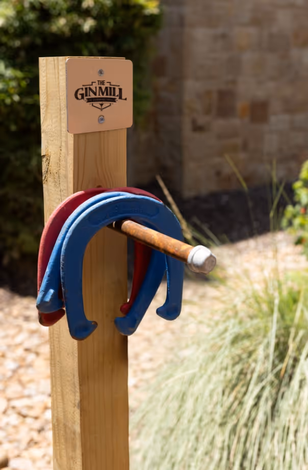 Horseshoe and wooden post with Ginmill logo in outdoor garden setting