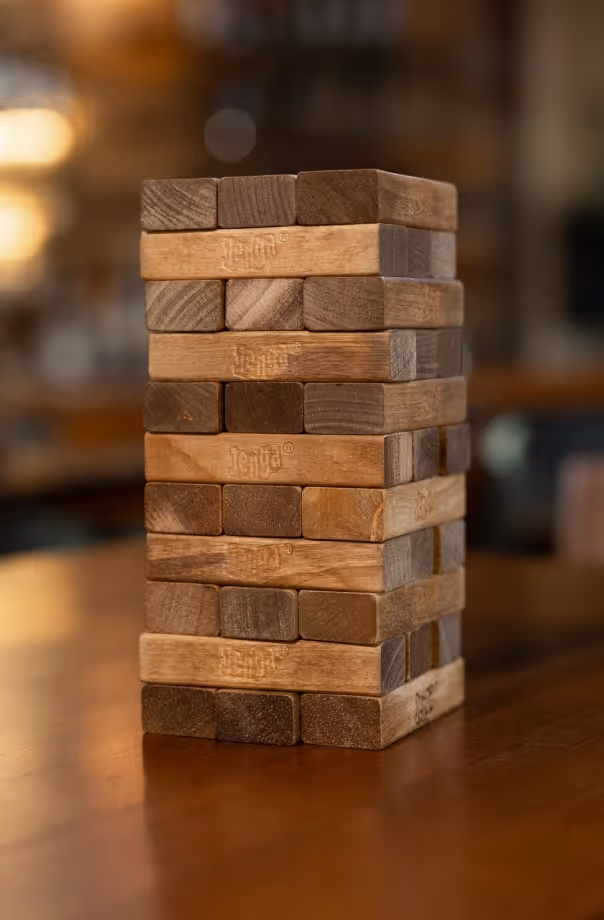Wooden Jenga tower stacked carefully on a blurred wooden surface