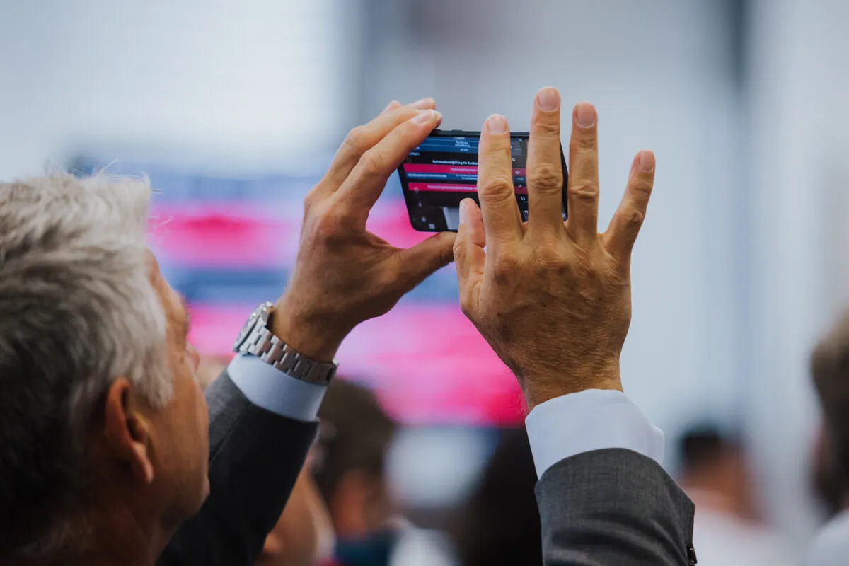 Eventfotograf München: Ein interessierter Zuhörer eines Events macht eine Bildnotiz mit dem Smartphone in München